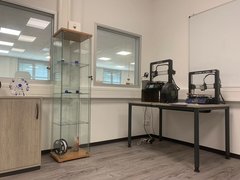 Blick in unseren EDV-Raum. Zu sehen ist eine halbhoher Schrank, eine Glasvitrine mit Ausstellungsstücken sowie ein Tisch, auf dem zwei 3D-Drucker stehen. 
