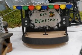 Zu sehen ist eine selbstgebaute kleine Bühne mit bunter Wimpelkette und zwei Lautsprechern im Vordergrund. Im Hintergrund ist die Aufschrift "Die Glöckchen" sowie gemalte Glöckchen zu sehen.