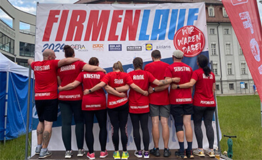 Gruppenfoto des Laufteams, Arm in Arm mit dem Rücken zur Kamera, vor dem Veranstaltungsbanner.