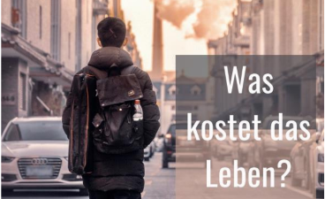 Was kostet das Leben? Foto: Auf dem Foto geht ein junger Mann eine Straße entlang. Er ist nur von hinten zu sehen. Am Straßenrand parken Autos.